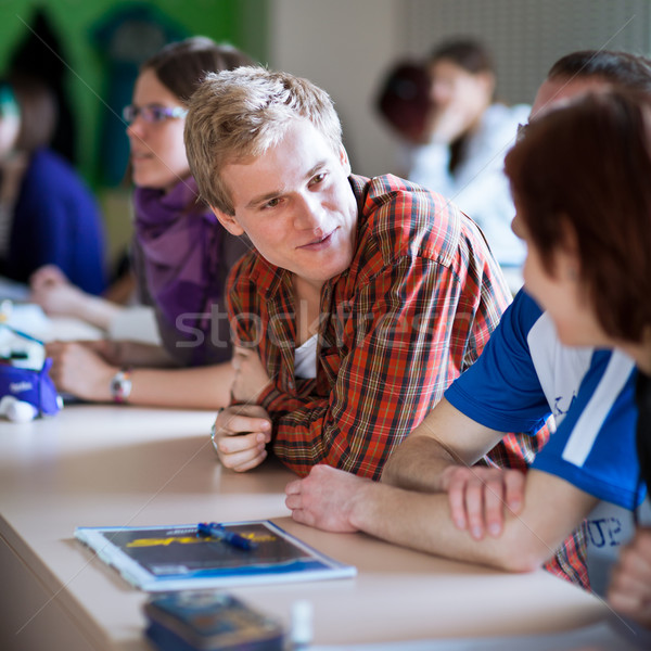 Handsome college student sitting in a classroom full of students Stock photo © lightpoet