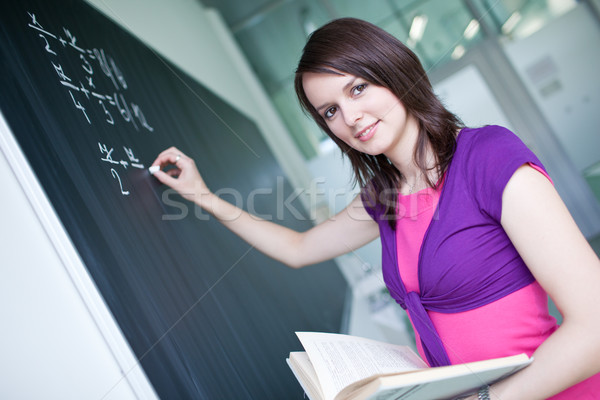 Stock photo: pretty young college student writing on the chalkboard/blackboar