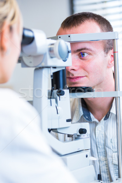 Handsome young man having his eyes examined by an eye doctor Stock photo © lightpoet