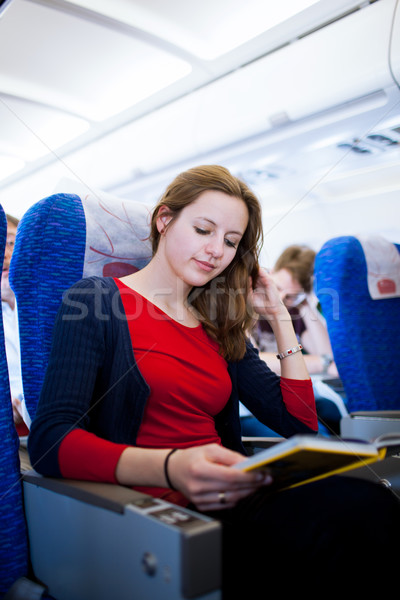 Mooie jonge vrouwelijke boord vliegtuigen lezing Stockfoto © lightpoet