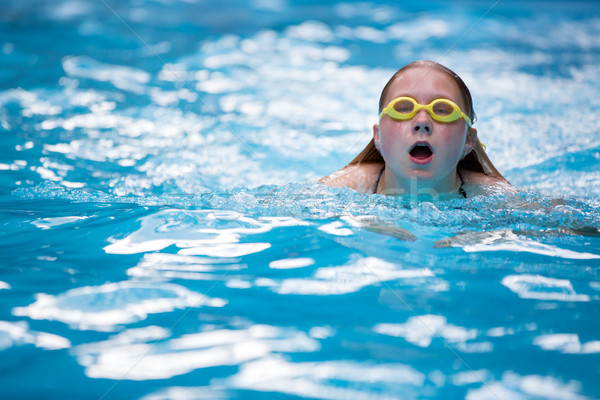 Young girl in goggles and cap swimming breast stroke style Stock photo © lightpoet