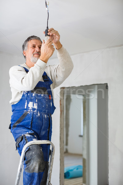 Stock photo: Senior man installing a bulb in a freshly renovated appartment