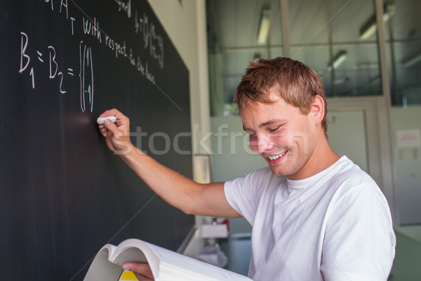 Stock photo: Handsome college student solving a math problem