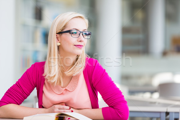 Stock photo: Pretty young college student in a library (shallow DOF; color to