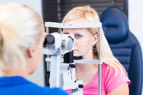 Pretty, young female patient having her eyes examined by an eye doctor Stock photo © lightpoet