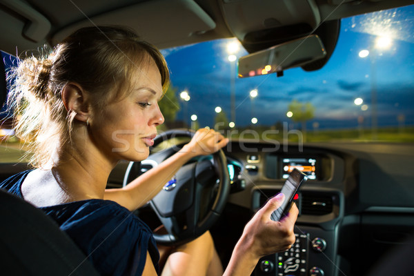 Pretty, young woman driving her modern car at night, in a city Stock photo © lightpoet