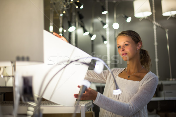 Stock photo: Pretty, young woman choosing the right light for her apartment