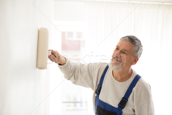 Stock photo: Senior man painting a wall in his home, 
