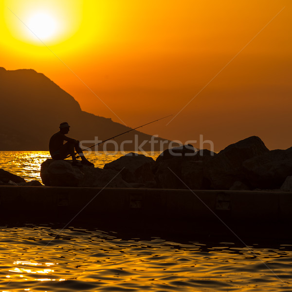 Fisherman's silhouette on the beach at colorful sunset Stock photo © lightpoet