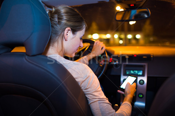 Pretty young woman using her smart phone while driving her car Stock photo © lightpoet