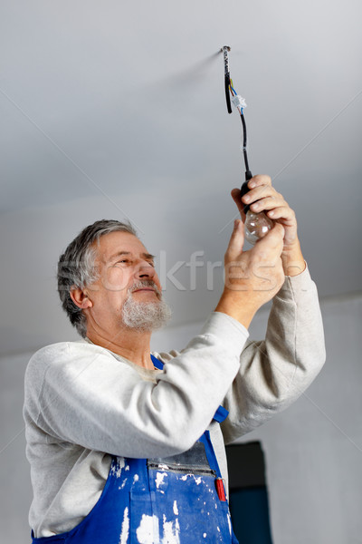 Senior man installing a bulb in a freshly renovated appartment Stock photo © lightpoet