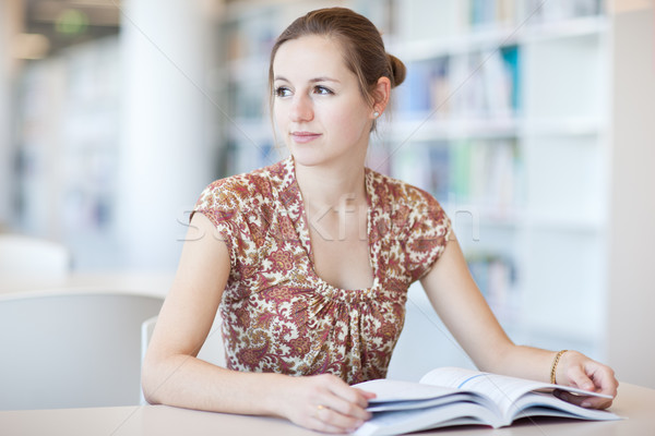 Stock photo: pretty young college student in a library (shallow DOF; color to