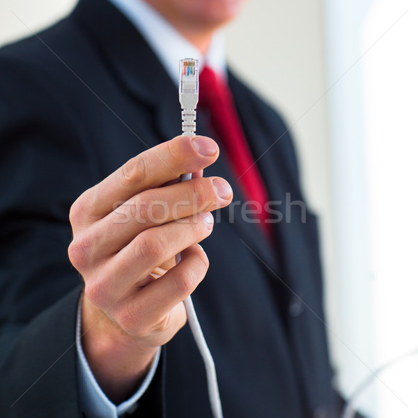 Young businessman holding an ethernet cable - stressing the impo Stock photo © lightpoet