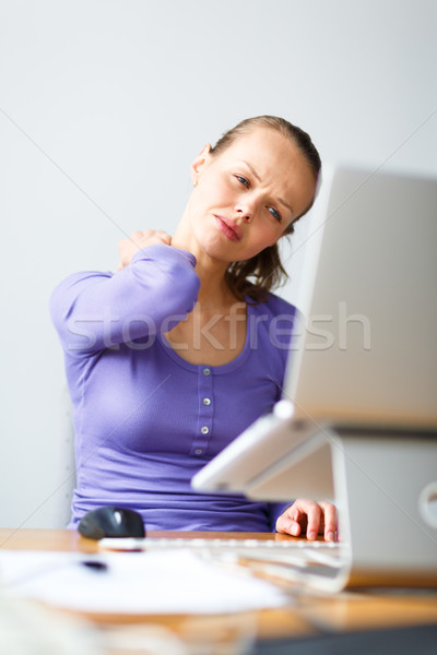 Stock photo: Working too hard - young woman working on a computer at an offic