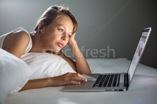 Pretty, young woman using her laptop computer in bed Stock photo © lightpoet