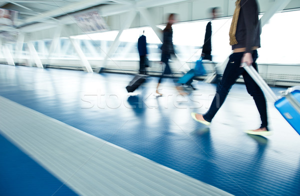 Stock photo: Airport rush: people with their suitcases walking along a corrid