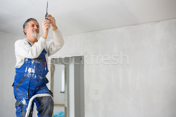 Senior man installing a bulb in a freshly renovated appartment Stock photo © lightpoet