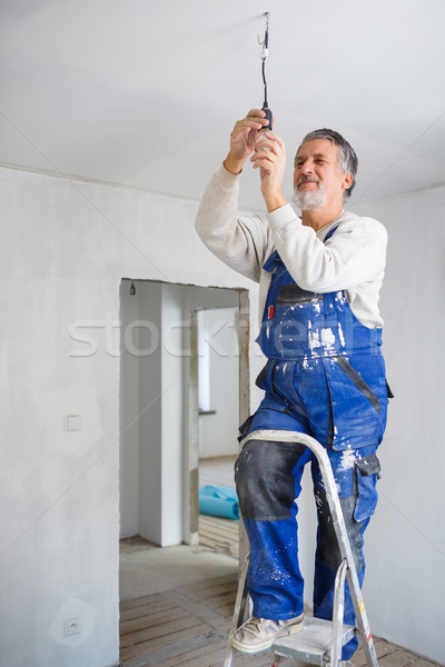 Stock photo: Senior man installing a bulb in a freshly renovated appartment