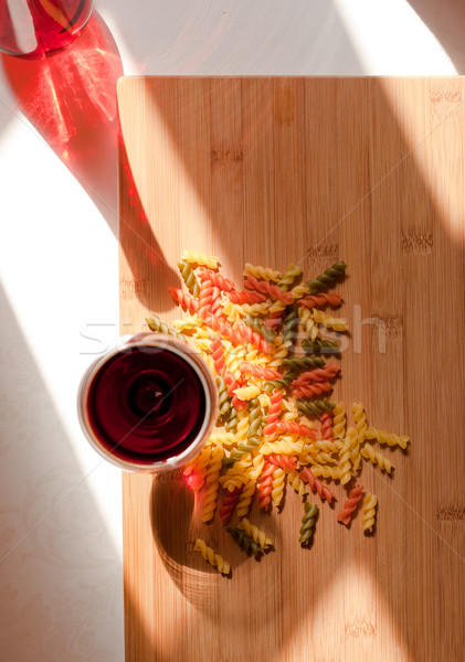 Still life with colorful pasta and glasss of red wine and colorful bottle in natural lighting. Stock photo © lithian