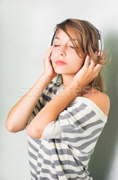 Beautiful young brunette immersed in music wearing headphones. Stock photo © lithian