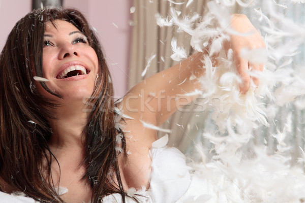 Fun woman throwing handful of feather and down Stock photo © lovleah