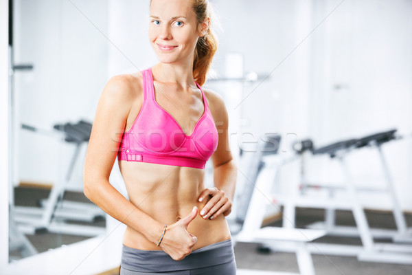 Portrait of happy athletic woman in gym showing thumb up. Stock photo © luckyraccoon