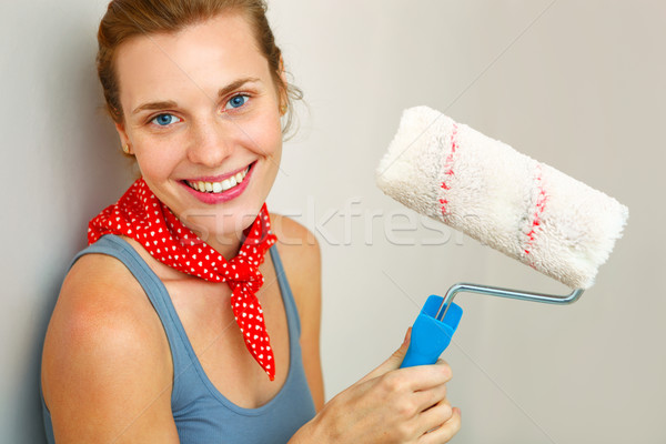 Happy woman with roller brush standing against wall. Stock photo © luckyraccoon
