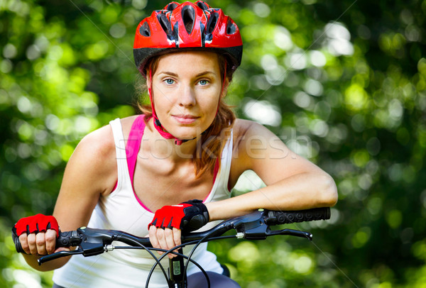 Happy Young woman leaned over the handlebars of her bike. Stock photo © luckyraccoon