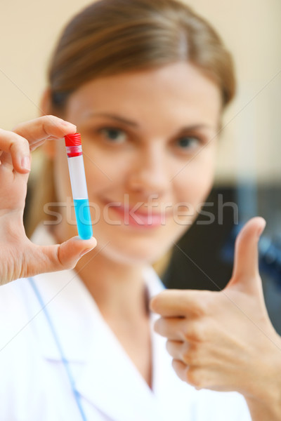 Happy young scientist holding samples with positive testing resu Stock photo © luckyraccoon