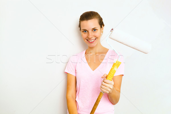 Happy woman with roller brush standing against wall. Stock photo © luckyraccoon