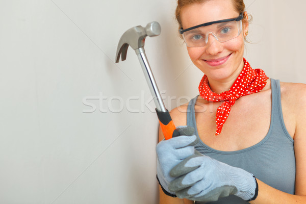 Young woman with hammer in hands looking at camera and smiling. Stock photo © luckyraccoon