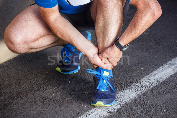 Stock photo: Broken twisted ankle - running sport injury. Male runner touchin