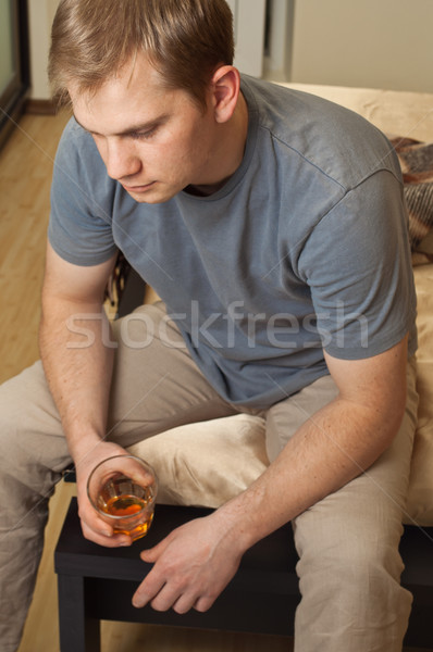 Portrait of young drunk man sitting with glass Stock photo © luckyraccoon