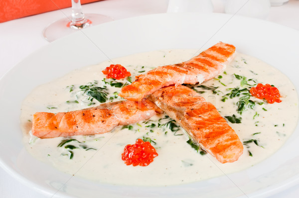 Closeup of a salmon mini steaks laid on spinach with Bianco sauce Stock photo © luckyraccoon