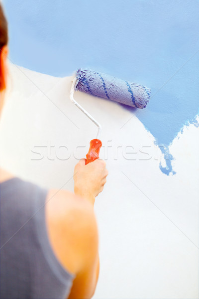 Young woman painting wall with roller brush. Stock photo © luckyraccoon
