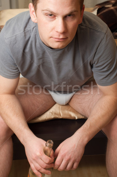 Stock photo: Portrait of young drunk man sitting with bottle