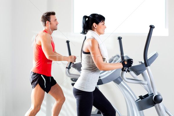 man and woman with elliptical cross trainer at gym Stock photo © lunamarina