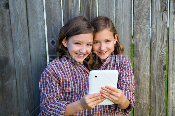 twin girls dressed up pretending be siamese and tablet pc Stock photo © lunamarina