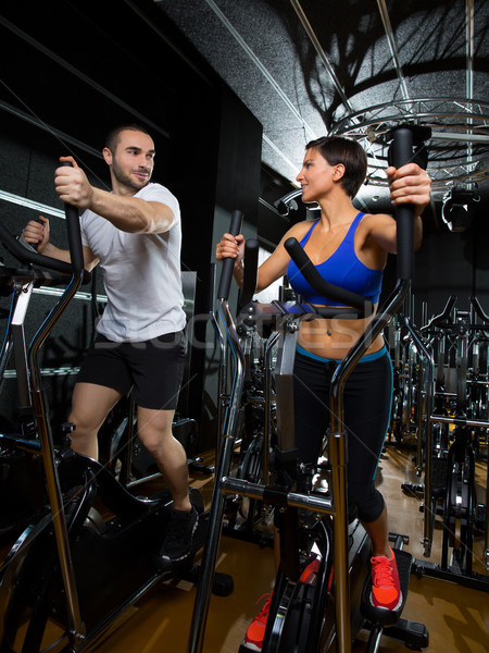 elliptical walker trainer man and woman at black gym Stock photo © lunamarina