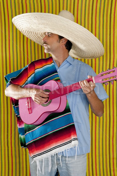 Mexican man serape poncho sombrero playing guitar Stock photo © lunamarina