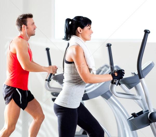 man and woman with elliptical cross trainer at gym Stock photo © lunamarina