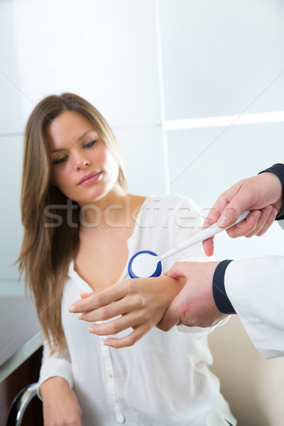 Doctor checking wrist with reflex round hammer to woman Stock photo © lunamarina