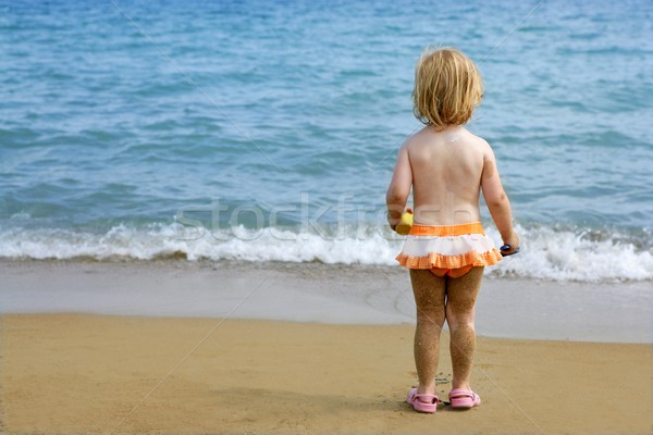 Blond little girl with sandy legs on the beach Stock photo © lunamarina