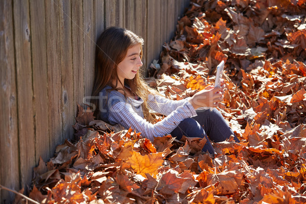 Kid girl playing tablet pc in autumn leaves Stock photo © lunamarina