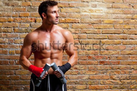 Stock photo: muscle shaped body man with weights on brick wall