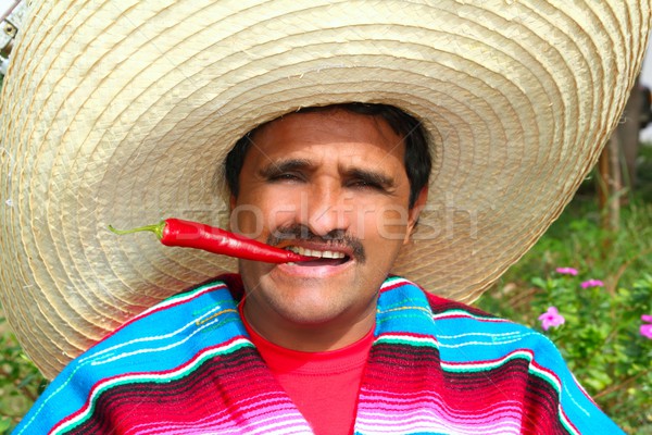 Mexican man poncho sombrero eating red hot chili Stock photo © lunamarina