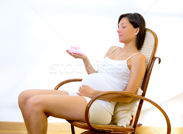 Gyönyörű terhes nő néz babacipők otthon ül Stock fotó © lunamarina