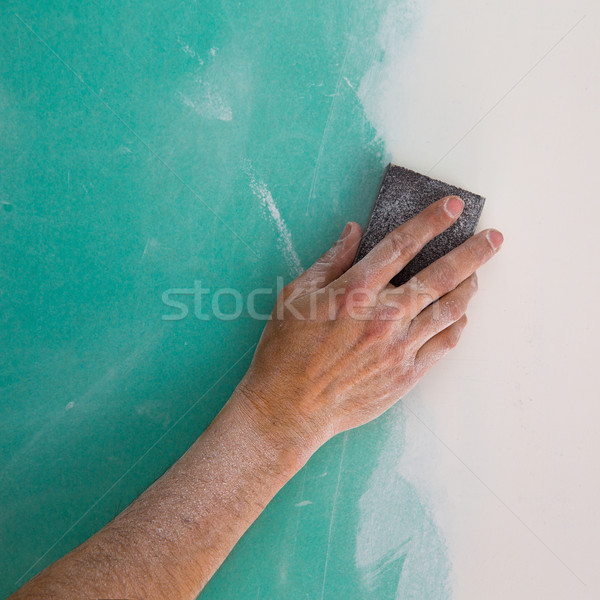 Stock photo: plastering man hand sanding the plaste in drywall seam
