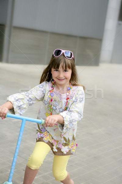 Stock photo: Brunette little girl with scooter in the city