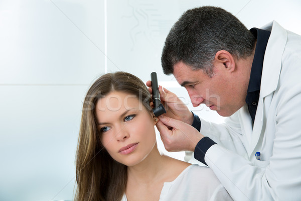 Doctor ENT checking ear with otoscope to woman patient Stock photo © lunamarina